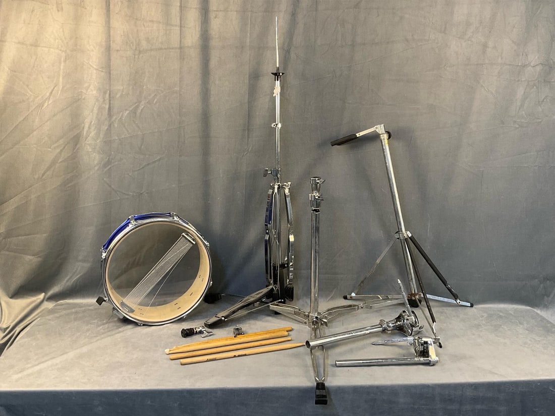 Miscellaneous Drumming: Lot of miscellaneous drumming items. One “d2 by drum” snare drum with loose parts. One stand with kick pedal, three partial stands with rusted areas. Five drumsticks. All in used condition. Sn