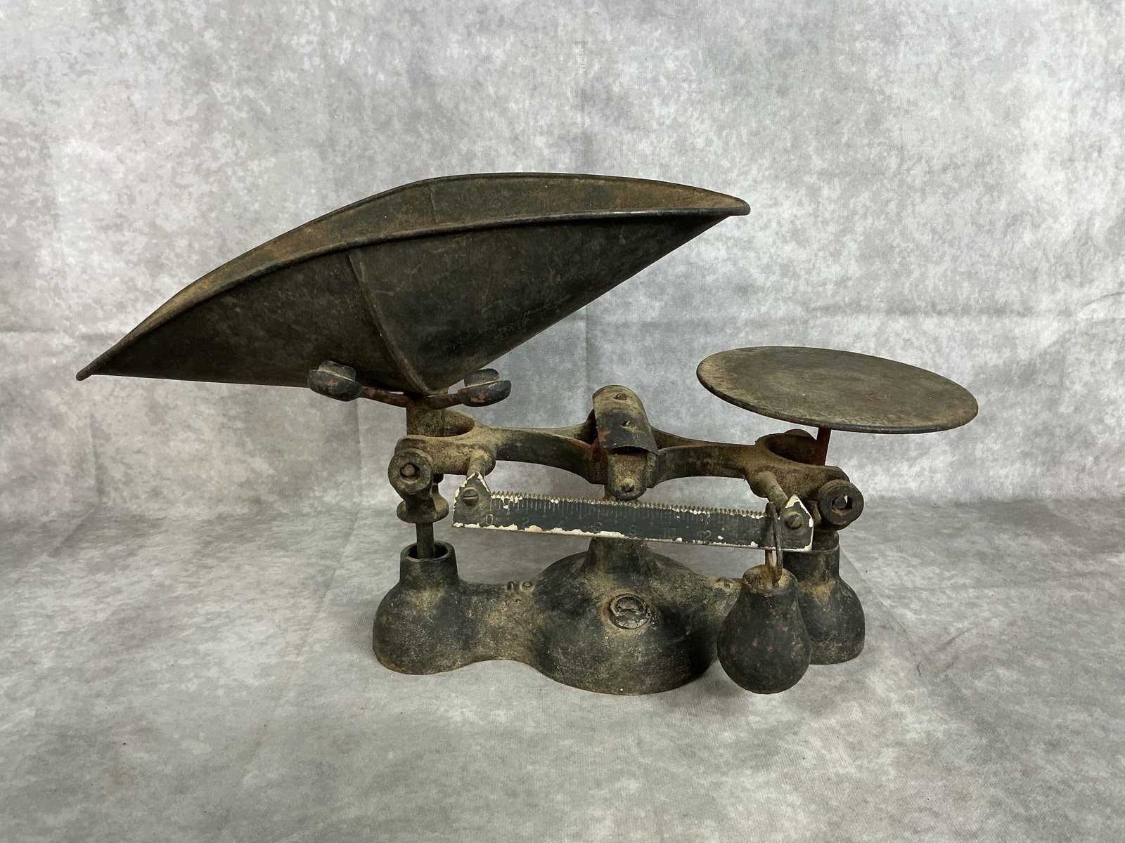 Antique Balance Scale: Late 1800s cast iron scale. Includes scoop pan, weight and scale. Paint loss, rust and wear present. Measures 17.5 inches long x 7 x 10 inches tall.