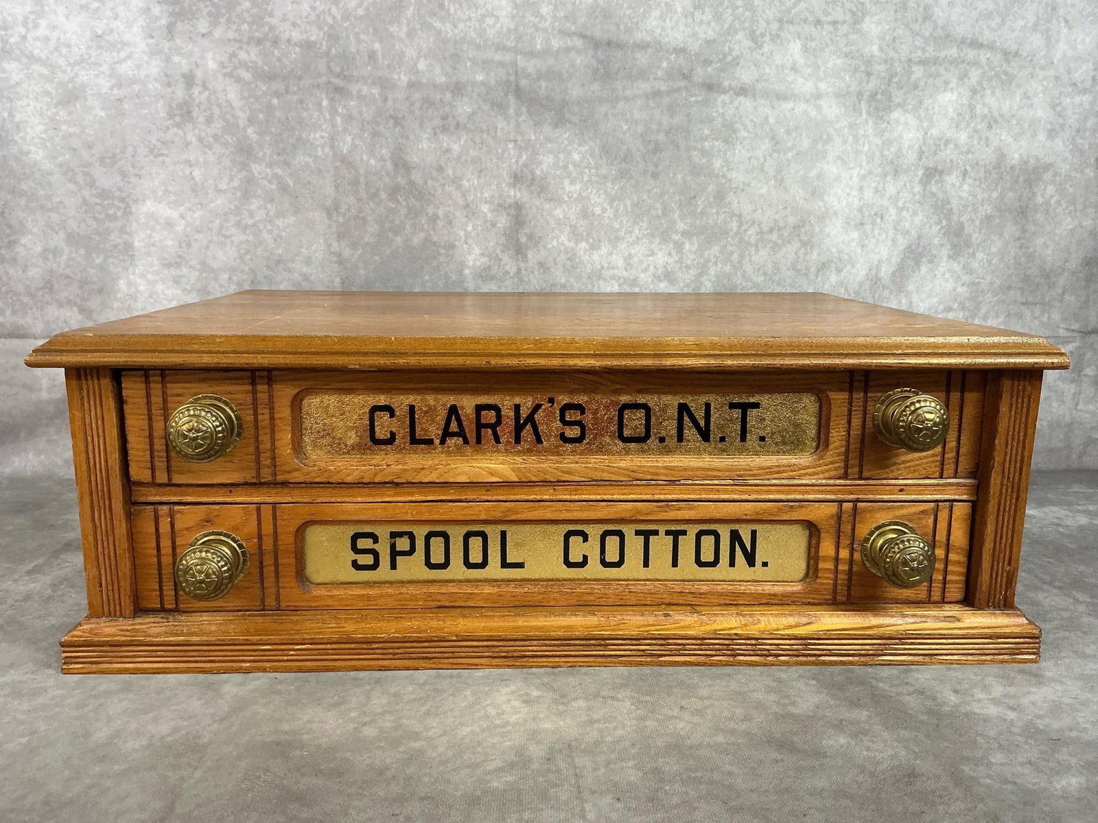 Clark's Spool Cabinet: Early 1900s spool cabinet. Wooden Clark's O.N.T. (Our new thread) Spool Cabinet with two drawers. Has a few scratches. Measures 22 inches wide x 15 x 7.5 inches tall.