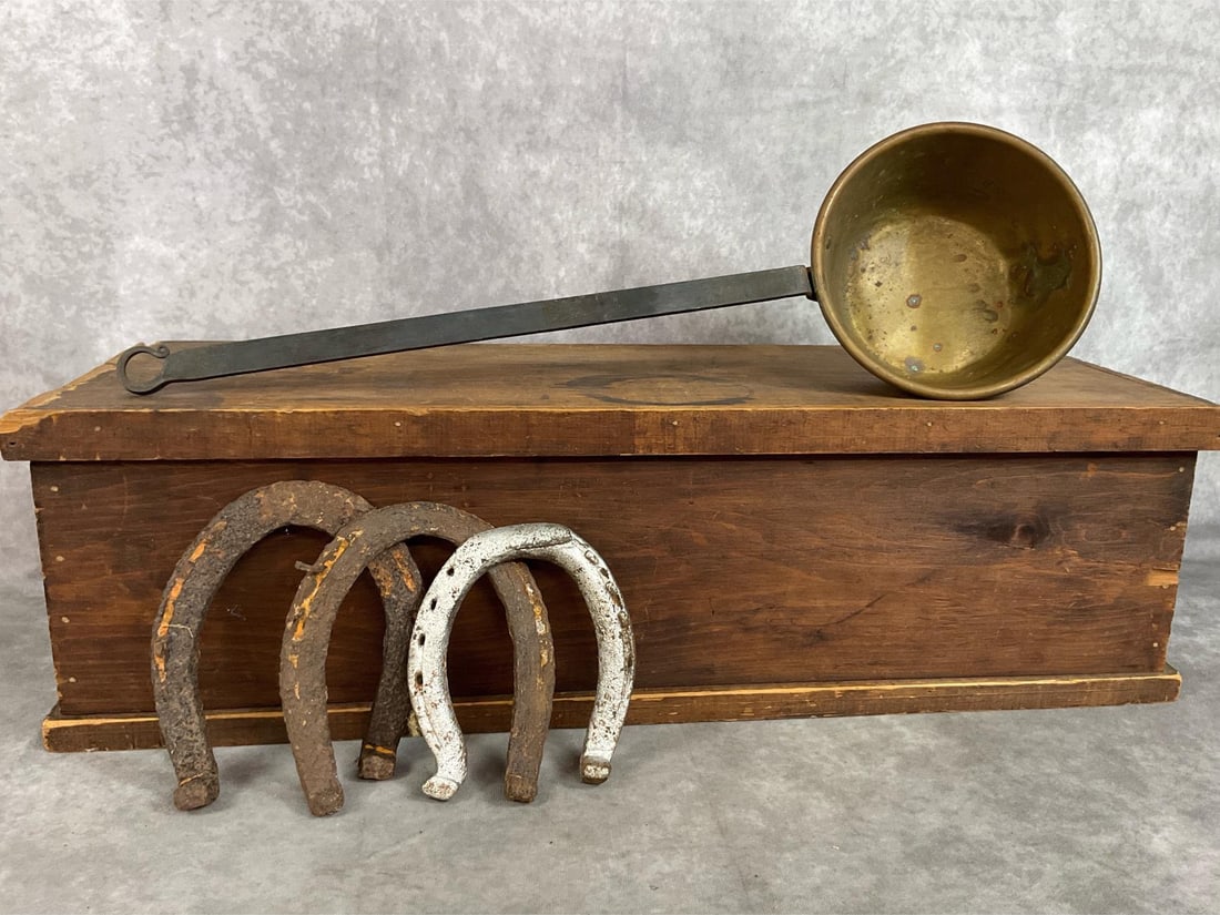 Antique Wooden Box, Brass Ladle & Horseshoes: Five late 1800s to early 1900s items. Storage wooden box with hinged lid and metal handles, brass ladle with long metal forged handle, and three horseshoes. Box has some nicks and wood loss, ladle