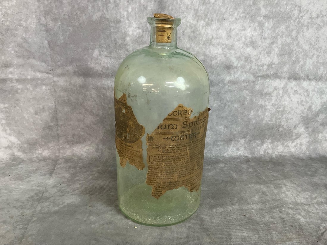 Rockbridge County Medicine Bottle: Late 1800's bottle. “Medical Alum Springs Water” from Rockbridge County, VA. Light green glass with cork stopper and label lists uses and amounts. Damage to paper label. Measures 4.5 inches