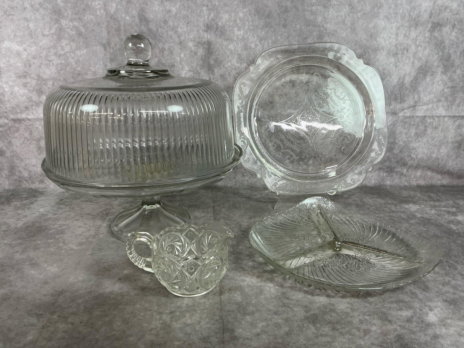 Anchor Hocking & More: Five early to late century glass pieces. Anchor Hocking ribbed glass dome cover, and pedestal stand. Madrid scroll pattern square plate by Federal glass, triangle shaped KIG three section pickle