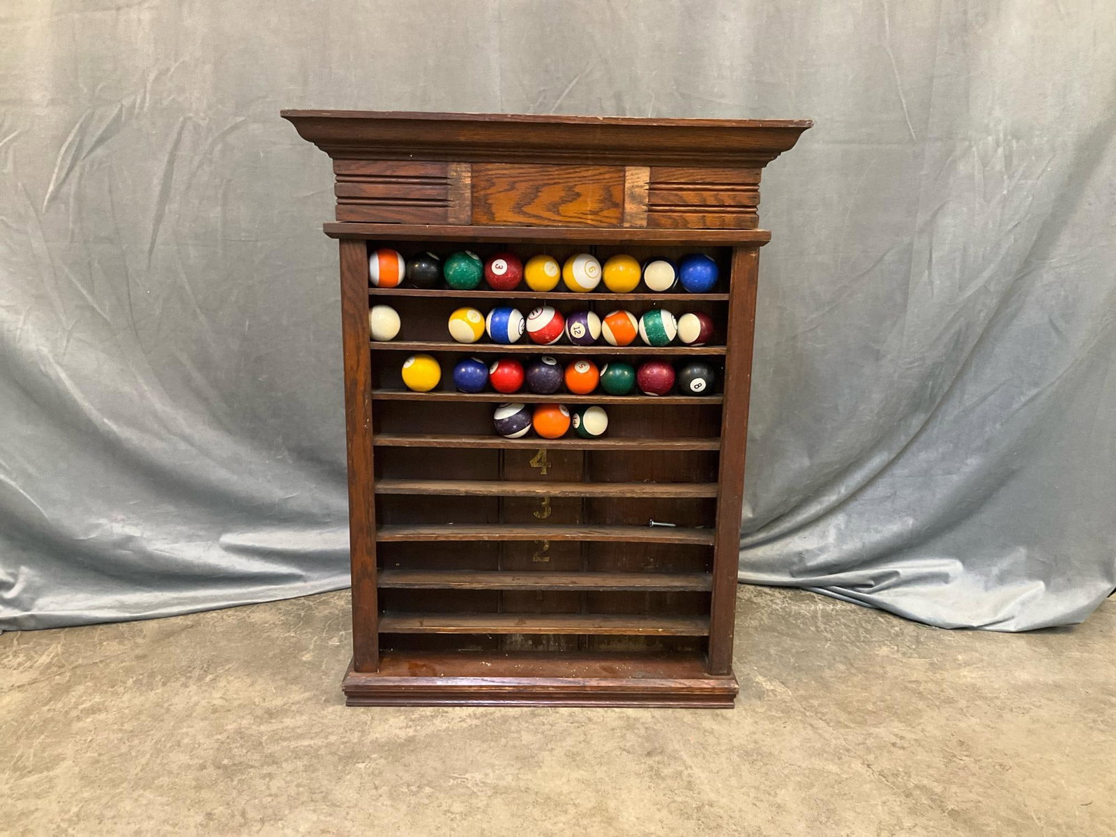 Pool Ball Rack: Late 19th century-early twentieth century oak pool ball wall mounted rack made by Brunswick -Balke-Collender Company, unmarked. Twenty eight pool balls total with duplicates. Gilded numbers 1-8