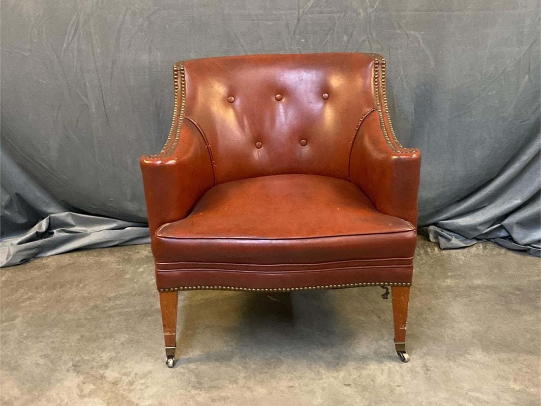 Club Chair: Late twentieth century Naugahyde club chair on brass castors with brass tack decoration. Separated stitching to backrest with various stains. Measures 29 inches wide x 29 x 29.5 inches tall.