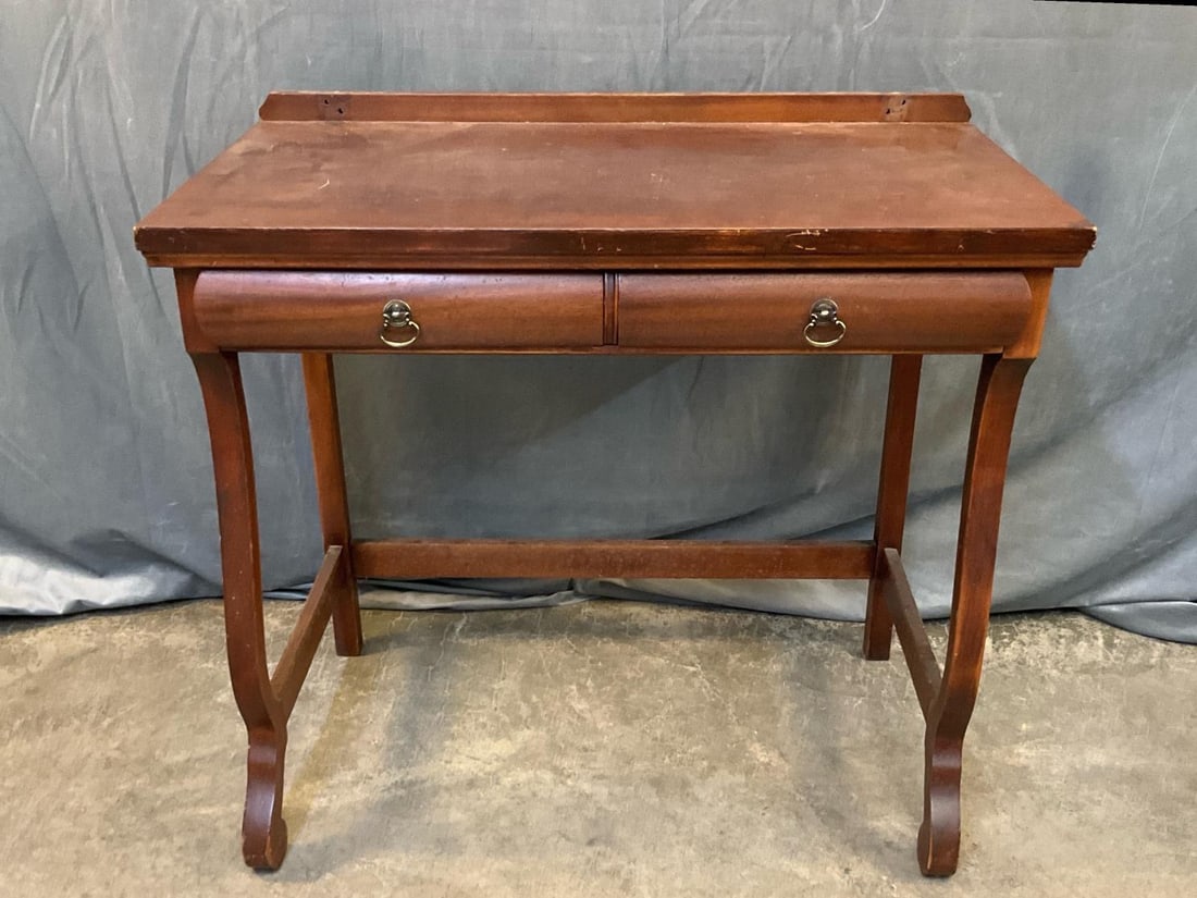 Writing Desk: Mid - twentieth century vintage mahogany writing desk with two drawers. Missing shelf or backsplash with loss to finish. Measures 34 inches wide x 20.25 x 31.25 inches tall.