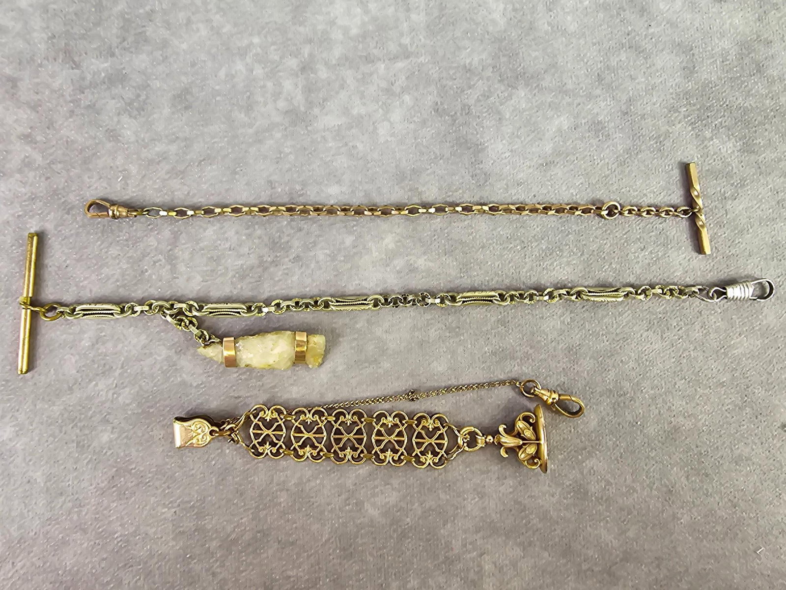Antique Watch Fobs: Three antique watch fobs, one has a quartz arrowhead attached to it, one has a patent date of 1903 and a fancy chain and monogrammed piece. All show signs of wear. Longest measures 10.5 inches long.