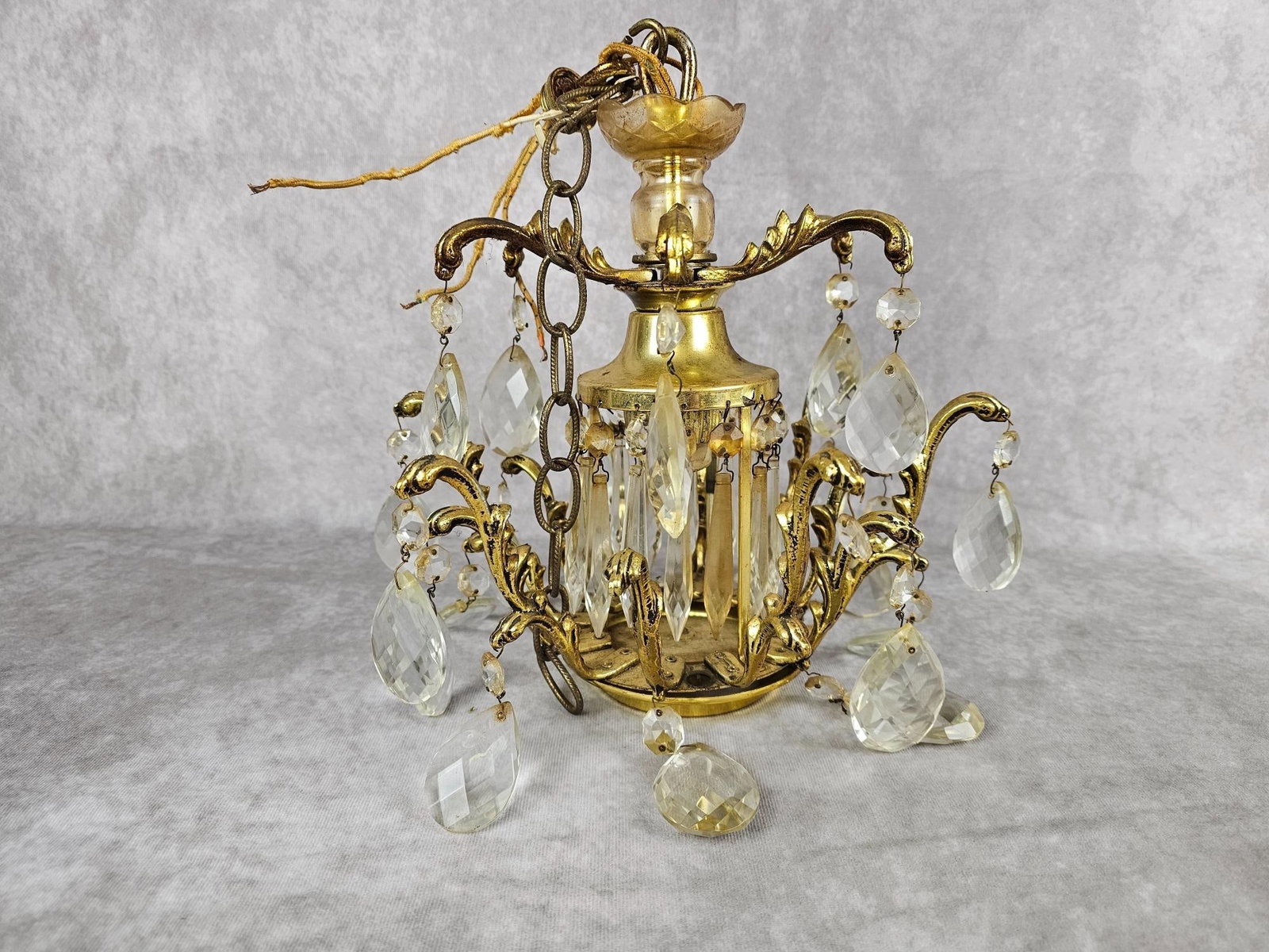 Prism Chandelier: Vintage gold toned metal chandelier with glass prisms. Complete with all prisms. Some rust to metal, staining and chips to some glass prisms. Measures 12 inches in diameter x 11.5 inches tall.