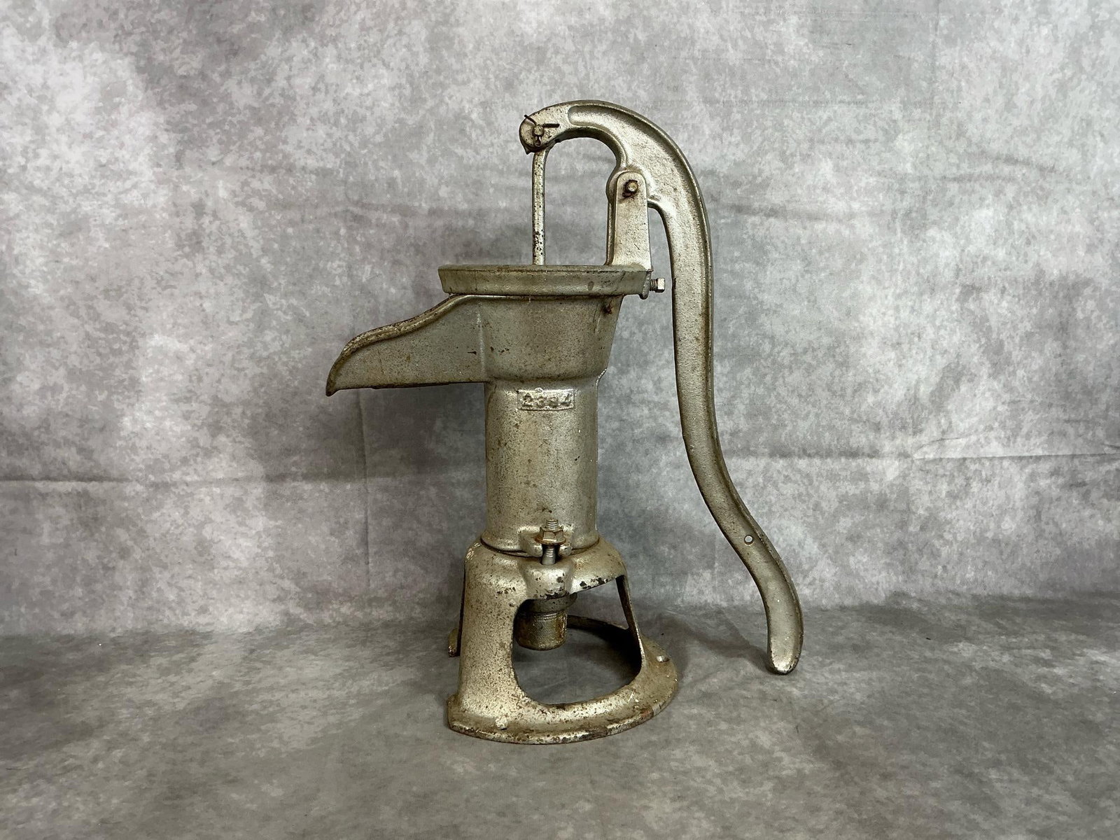 Hand Water Pump: Mid century cast iron water pump. Number 2384 cast iron hand pump with working handle. Rust present. Measures 13 inches from handle to spout x 8 inches diameter at base x 18.5 inches tall.