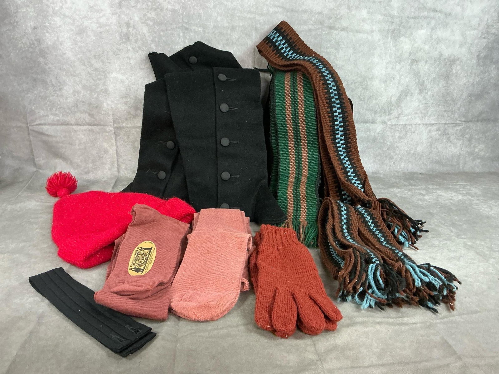 Spats, Sashes, Gloves, & Socks: Ten reenactor's clothing items. Black spats, two large sashes and two small sashes, and gloves. Two pair of mauve socks size 10-13, and red wool beanie. Items worn, but otherwise in good condition.