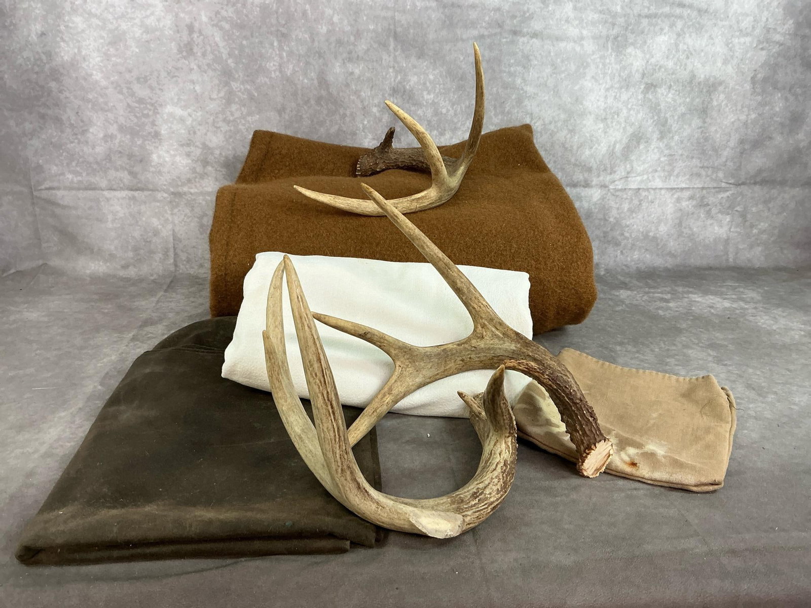 Reenactor's Blanket, Tarp, Antlers & More: Four fabric pieces and three antlers. Thick brown blanket, dark canvas, white cotton cloth, and small cloth bag. Authentic antlers. Fabrics have stains. Blanket measures 64 inches wide x 78 inches