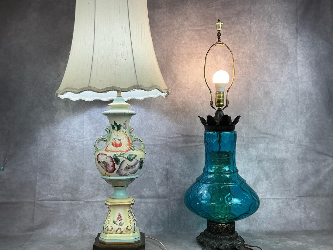 Vintage Table Lamps: Two mid century electric table lamps. Blue textured body lamp with ornate metal base, missing lampshade. Ornate urn style lamp with metal base and floral with gilt accents. Both work. Lampshade is