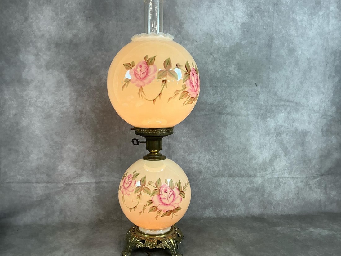 Two Globe Parlor Lamp: Mid century "Gone with the Wind" style lamp. Hand painted cream colored glass globes with pink roses. Ornate brass base and three way electric lamp. In good condition. Measures 10 inches in diameter