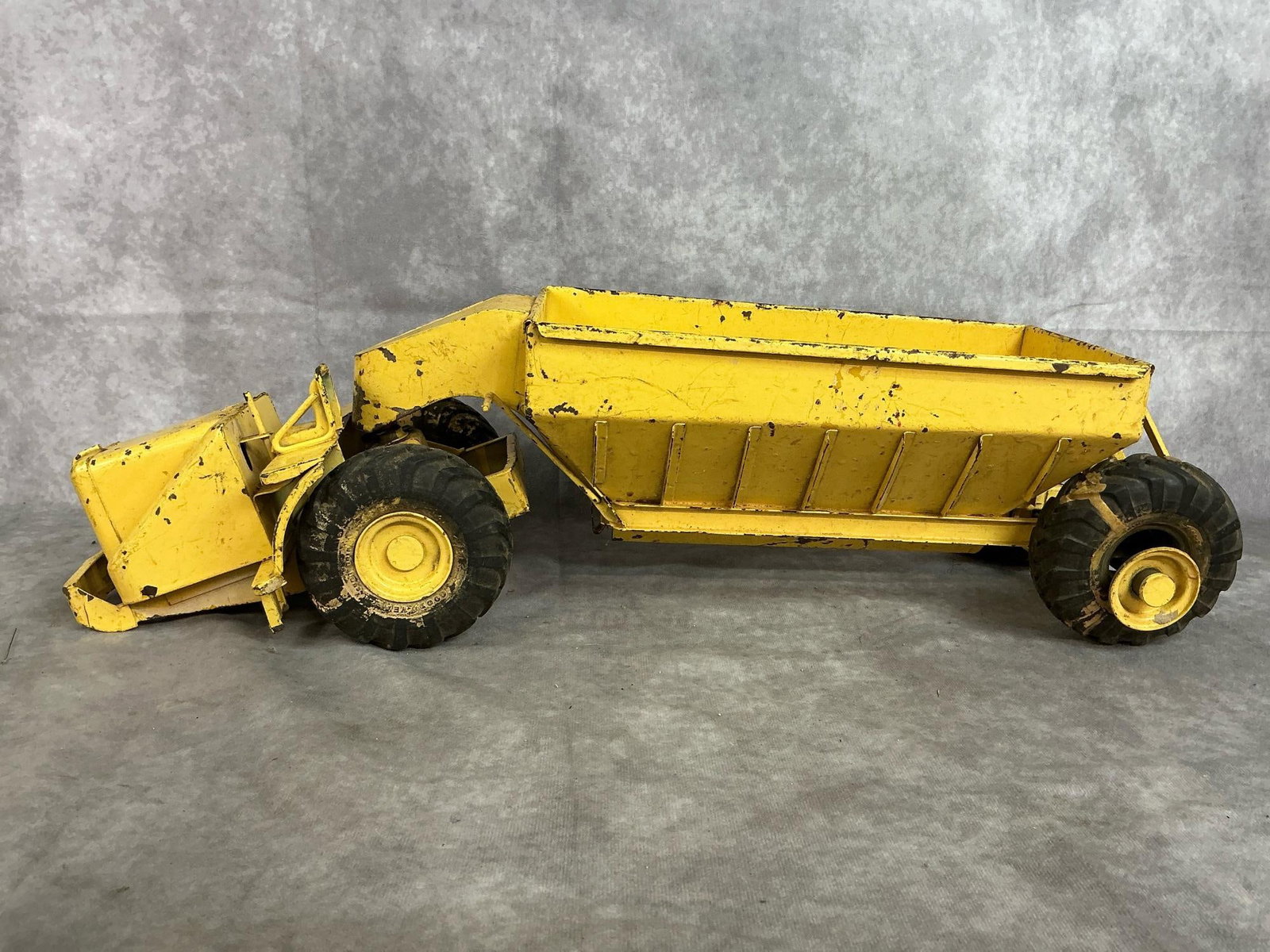 Toy Earth Mover: 1940's Doepke Model Woolridge bottom dump earth mover. Pressed steel with Goodyear tires. Back tires are loose, toy has rust and wear present. Measures 23 inches long x 8 x 7 inches tall.