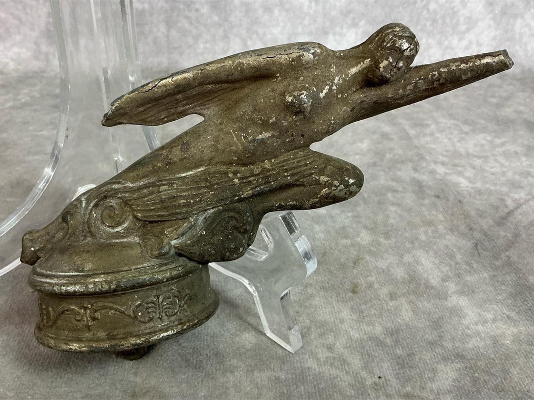 Studebaker Auto Hood Ornament: 1920's Studebaker car hood ornament. "Flying Goddess" cast metal with plated finish. A few cracks present and heavy tarnish. Measures 7 inches long x 2.5 x 4 inches tall.