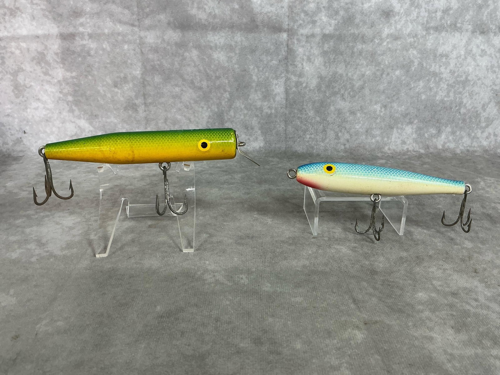 Vintage Wooden Lures: Two vintage wooden fishing lures. Green and yellow lure has diving lip and 2 treble hooks. And Pfluegar Ballerina minnow blue lure. In good condition. Green lure measures 5.5 inches long x 1 inch