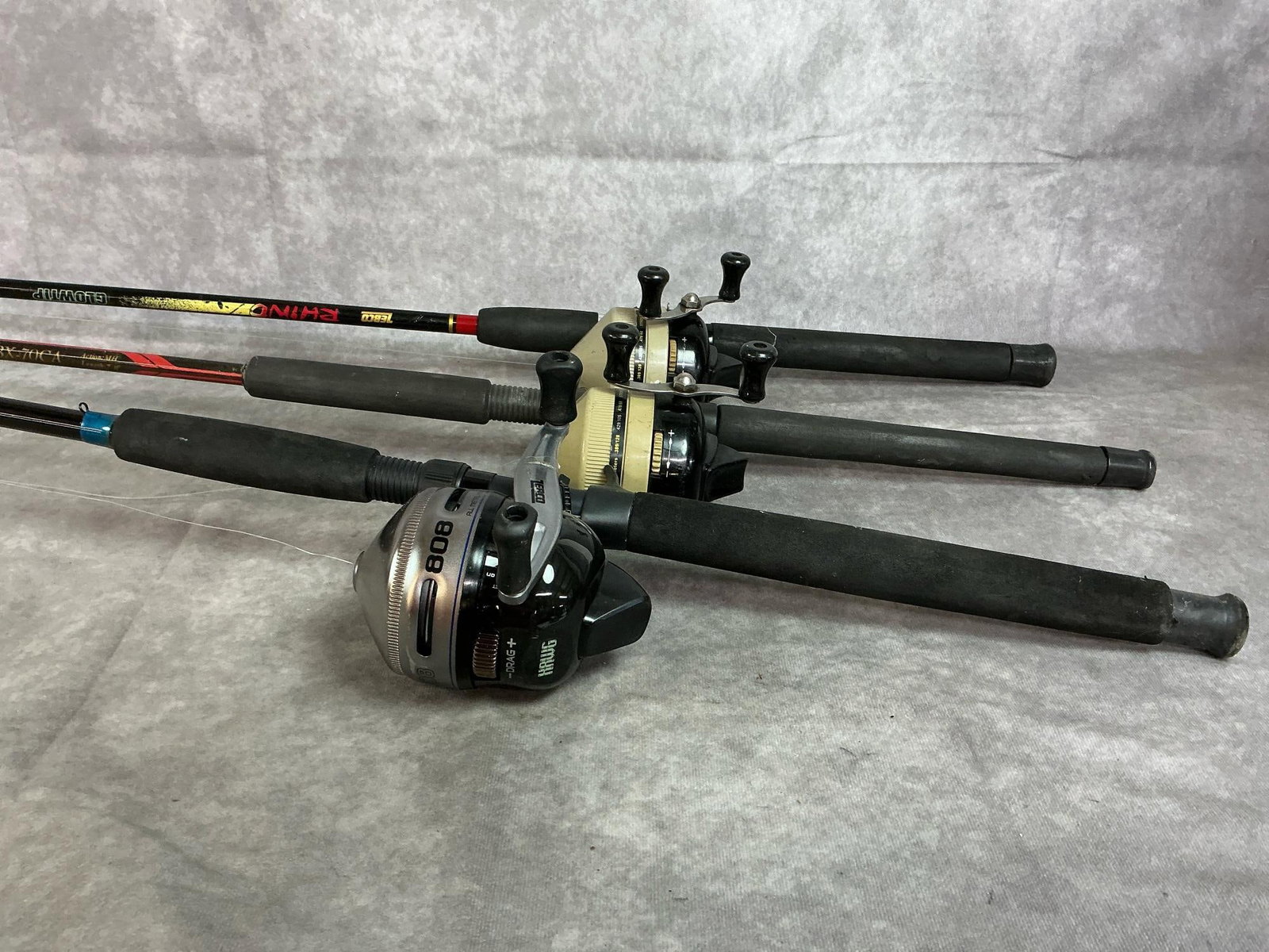 Zebco Reels with Assorted Rods: Three Zebco 808 reels for salt water fishing. Push button Magnum drag system. Rods include Rhino Glow Tip, Zebco Boss Hawg, and Silstar BX graphite. In good condition. Fishing rods measure 81 inches
