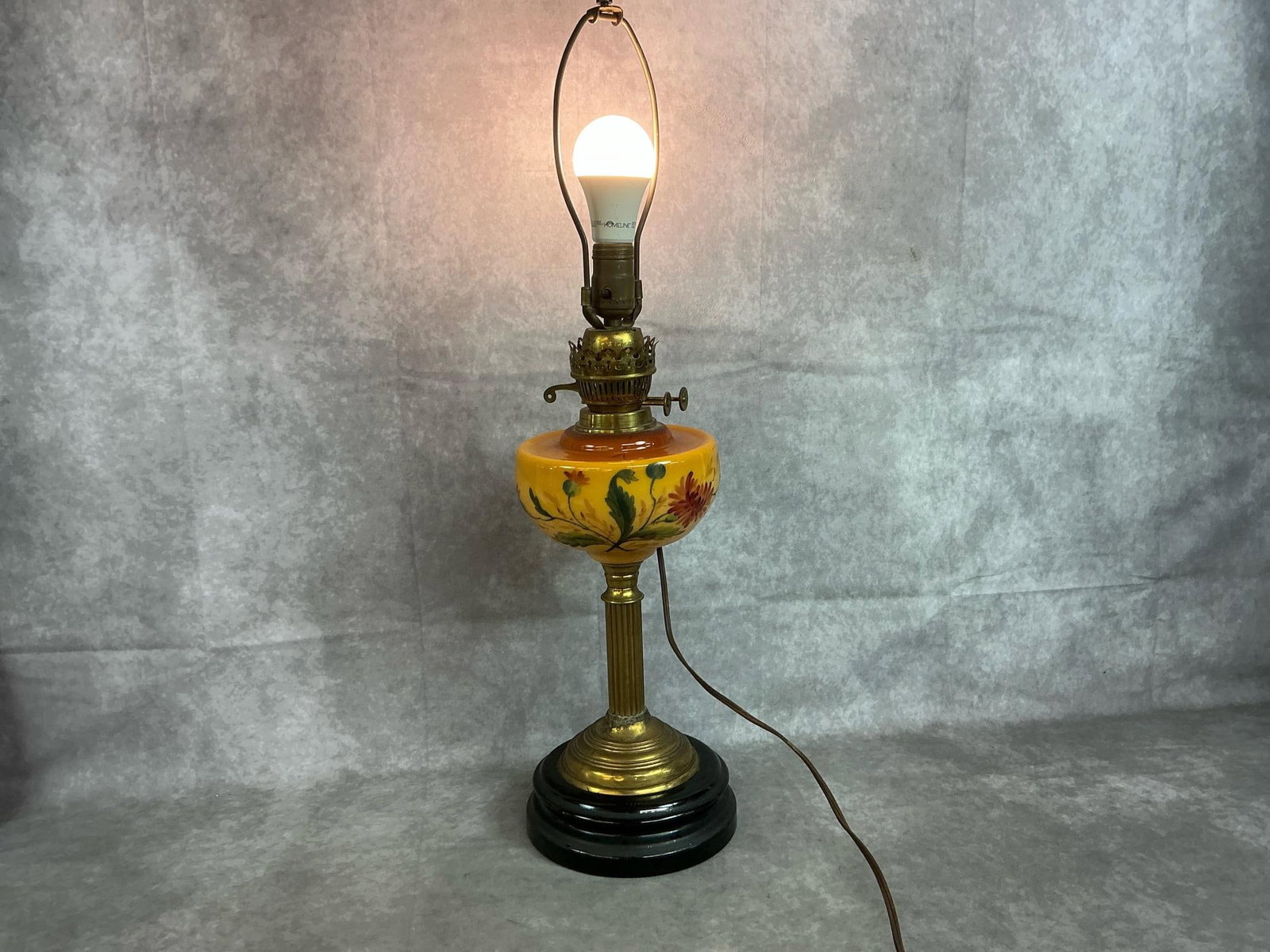 Antique Converted Oil Lamp: Early 1900's oil lamp converted to electric. John Wanamaker brass and gold glass with floral painted font. In good working condition. Measures 7.5 inches in diameter x 27 inches tall.