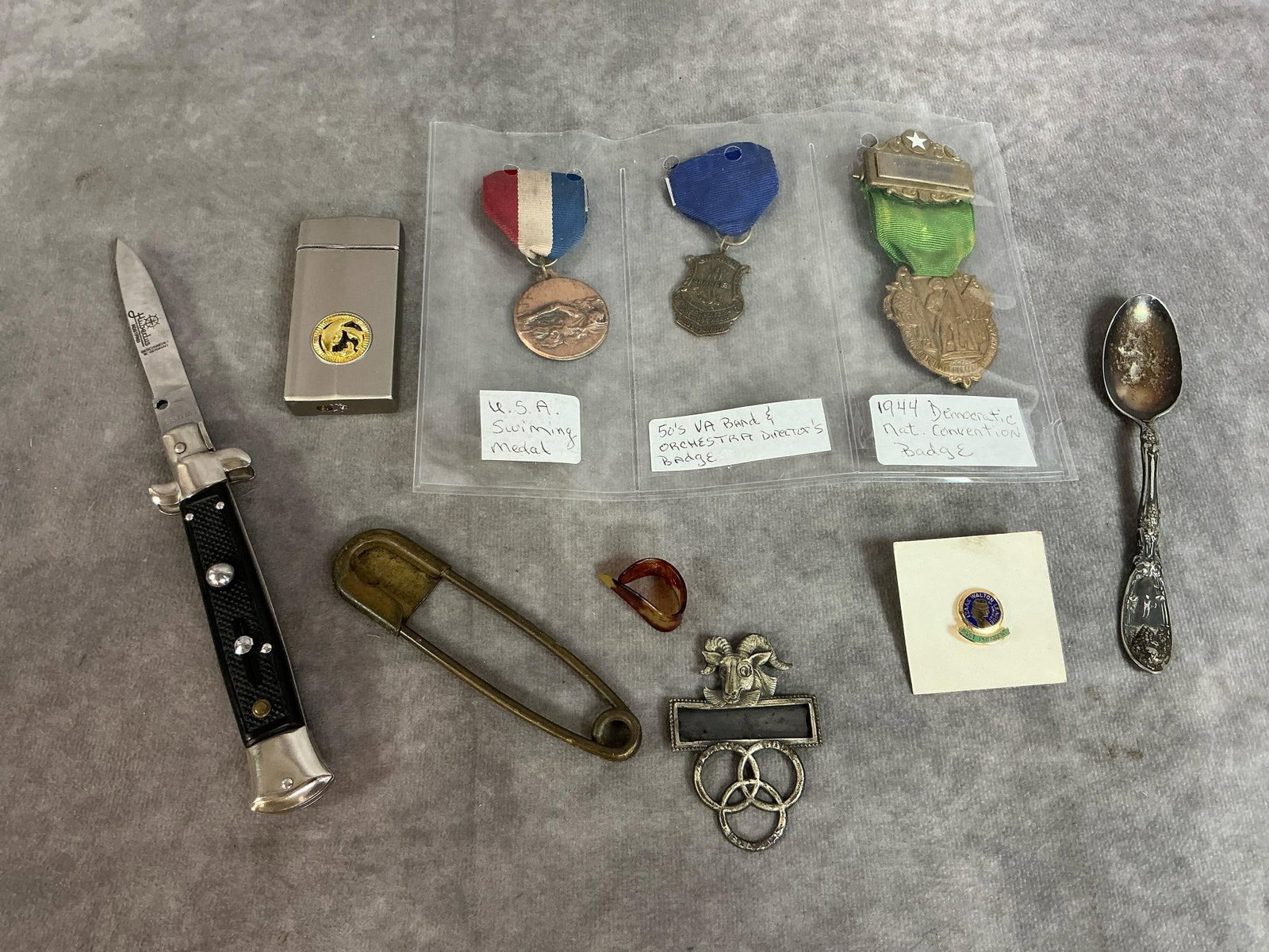 Vintage Badges, Switchblade, Lighter & More: Ten early to late 1900's items. Three ribbon medals, goat Ballantine Beer Employee badge, Hubertus switchblade, Roger's spoon, Zenith lighter, and more. Tarnish and wear present. Switchblade measures