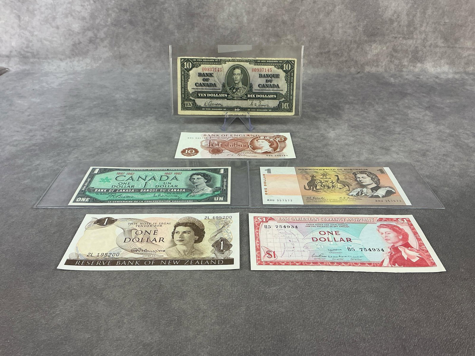 Foreign Currency: Lot of six foreign currency bills with five featuring Queen Elizabeth and one 1937 Canadian ten dollar bank note featuring King George VI. All in good condition and circulated. Several with plastic