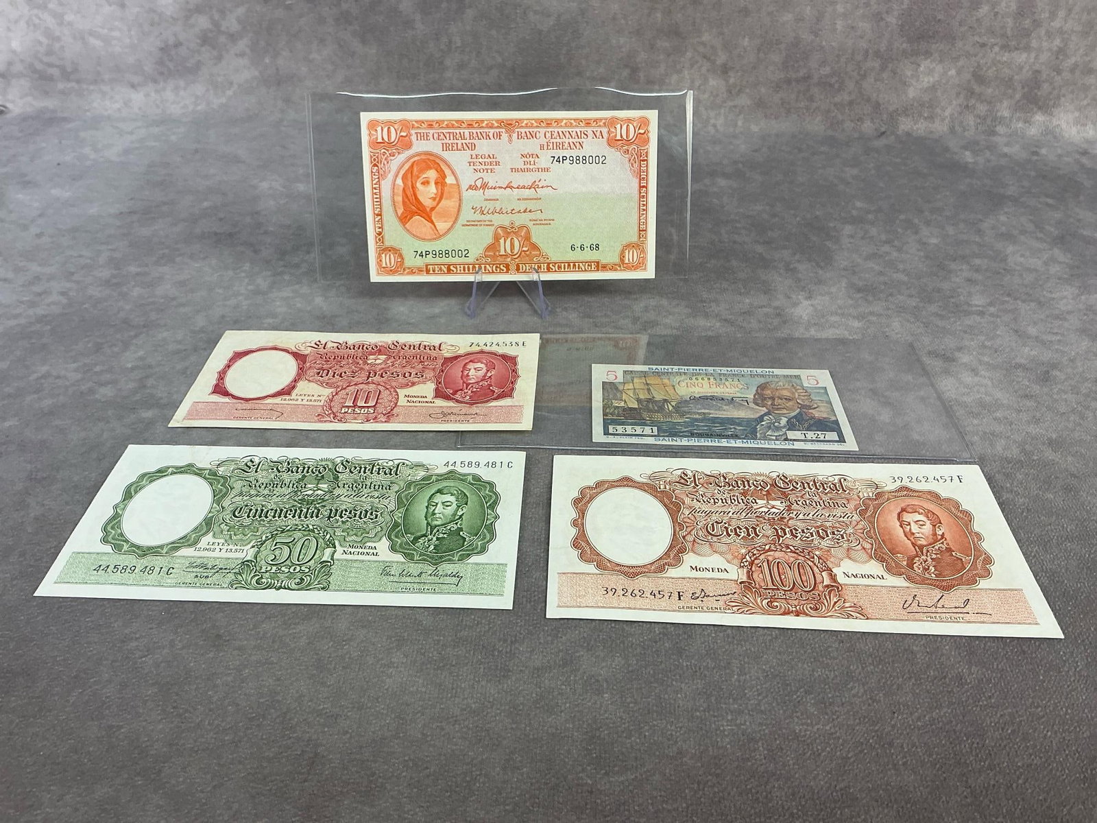 Foreign Currency: Lot of five foreign currency bills including three 1950s throu 1960s peso banknotes from Argentine, one 1950s five Francs from the territory of Saint Pierre and one 1968 Irish 10 shilling known as