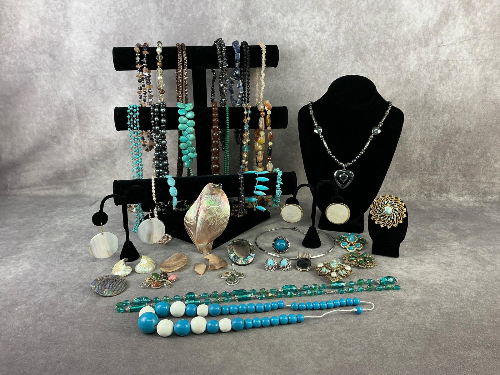 Costume Jewelry: Over thirty five pieces of costume jewelry including necklaces, bracelets, brooches, earrings, pendants, and beads. Large shell pendant and shell earrings, stone necklaces, turquoise colored beads