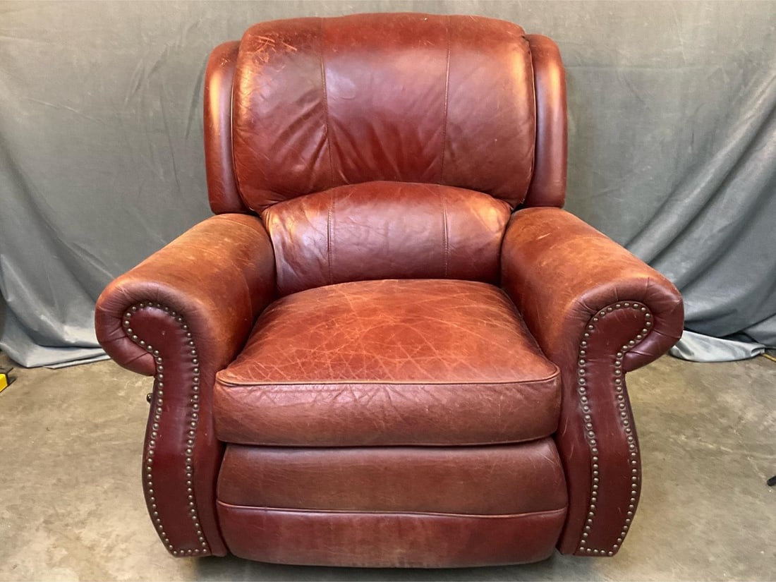 Reclining Chair: Late 20th century red leather adjustable recliner with brass tack decoration. Scuffs to leather, otherwise good condition. Measures 43 inches wide x 39 x 38.5 inches tall.