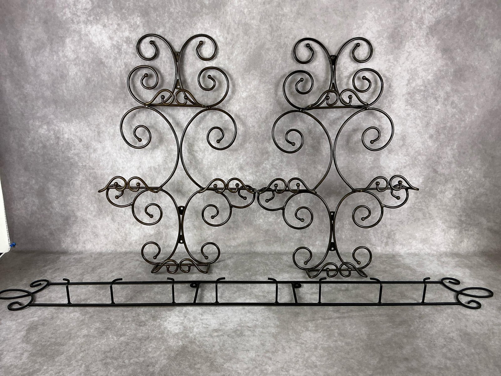 Plate Holders: Three decorative plate racks or plate holders. Two with a brushed bronze finish and one matte black. Good condition. Largest measures 45.25 inches long x 5.25 inches tall.
