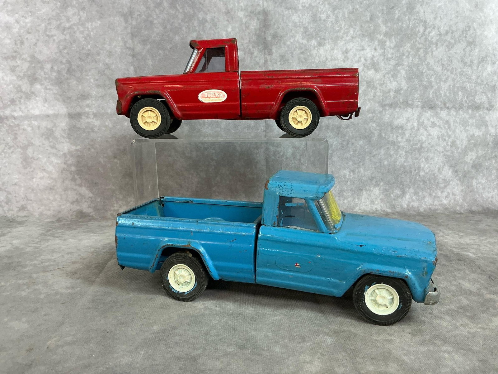 Tonka Metal Trucks: Two 1960's Tonka Trucks. Red and blue metal Jeep toy trucks. Both have paint loss and blue truck has yellow and white paint on windshield and tailgate. Each measures 9 inches long x 3.25 x 3.5 inches