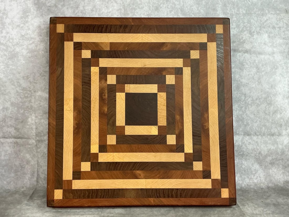 Inlaid Cutting Board: Wooden handmade cutting board. Inlaid variety of wood. Felt pads on bottom. In good condition. Measures 18 inches wide x 2 x 18.5 inches high.