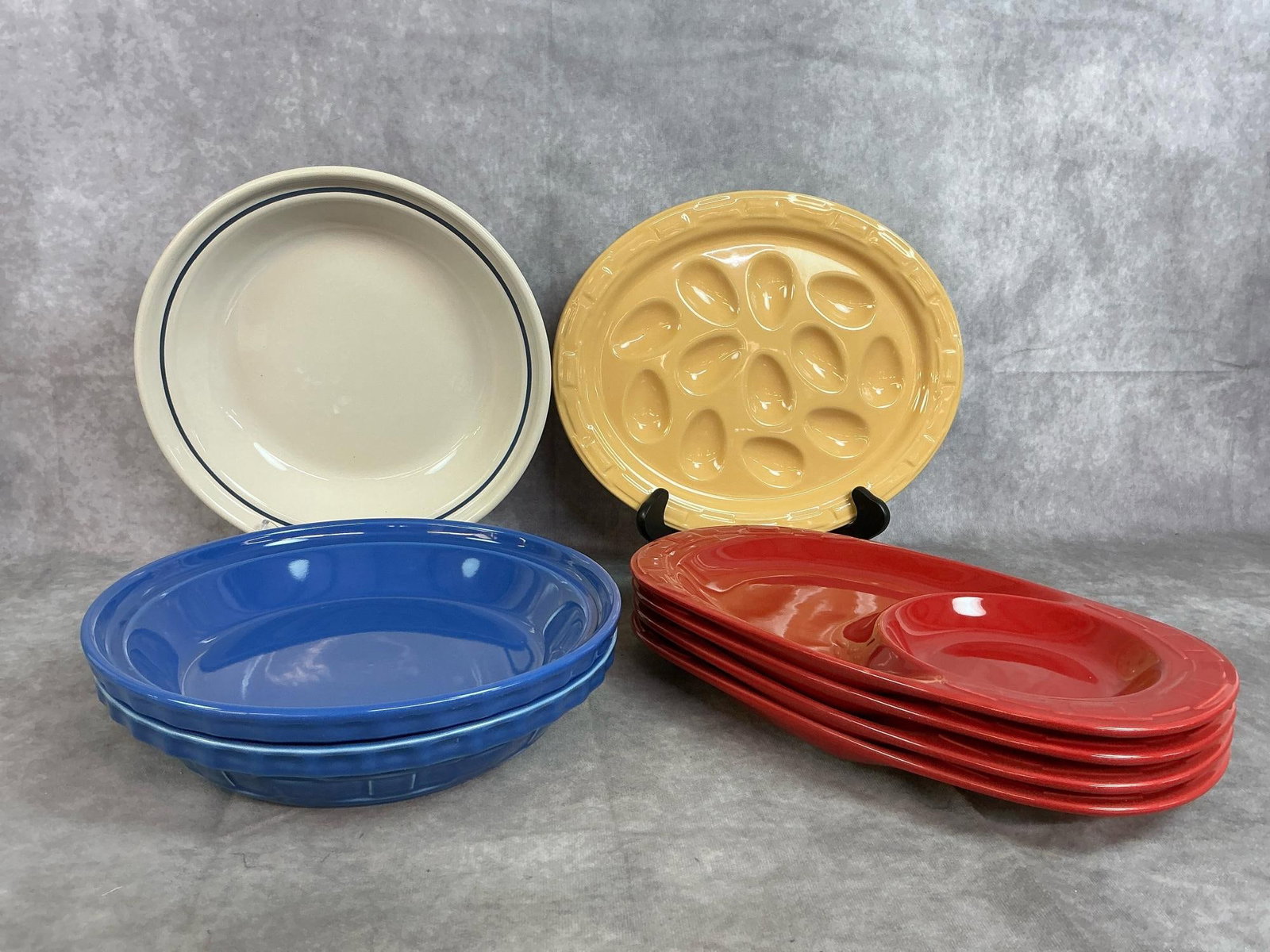 Longaberger Pottery: Eight pieces of Longaberger pottery. Includes yellow egg plate, three pie plates, and Paprika colored soup and sandwich plates. All in good condition. Soup and sandwich plates measure 13 inches long