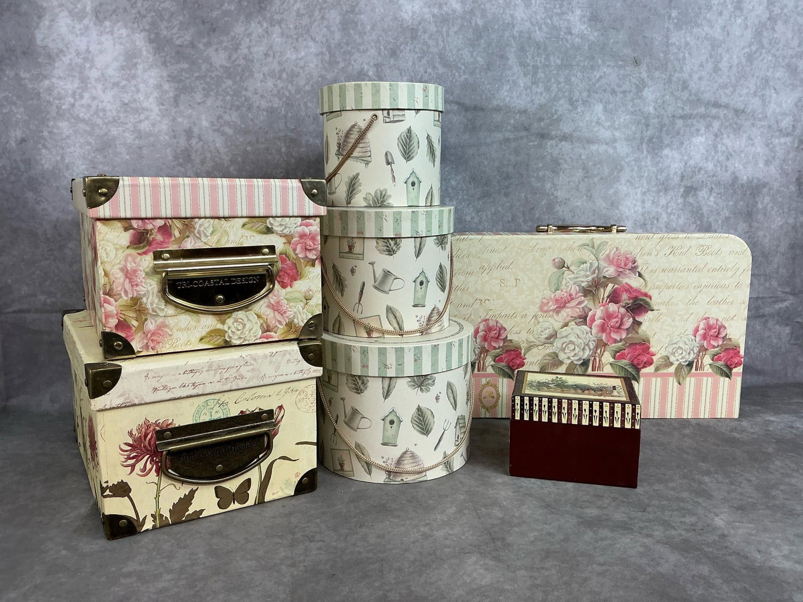 Decorative Storage Boxes: Seven cardboard with metal accents boxes. Suitcase style and card box style are shabby chic floral boxes. Stacking set of three round Pfaltzgraff Naturewood boxes and Wee Baskets small box. In good