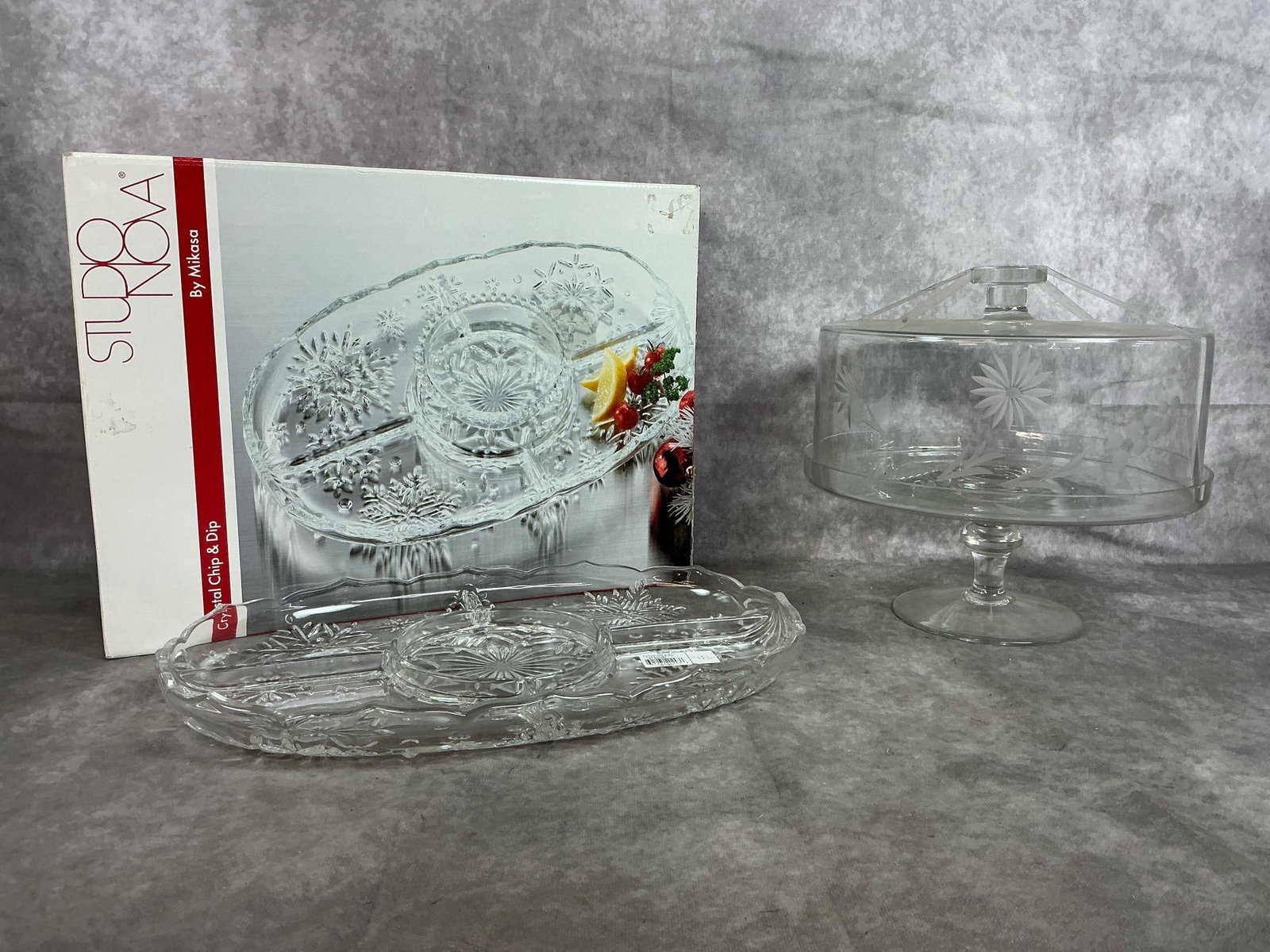 Mikasa Crystal Dish & Pedestal Cake Stand: Vintage pedestal etched glass cake stand with domed lid. Studio Nova Mikasa crystal snowflake chip and dip tray, never used. Both in good condition. Tray box measures 16.5 inches wide x 12 x 3.25