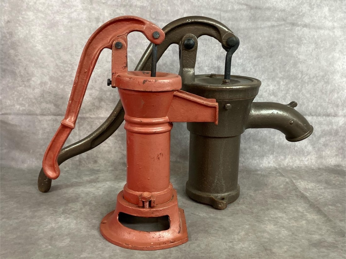 Cast Iron Hand Pumps: Two vintage cast iron pitcher pumps. Black pump measures 7 inches in diameter at top x 17 inches tall, with 18 inches spout to handle. Slight paint loss on red pump, otherwise both in good condition.