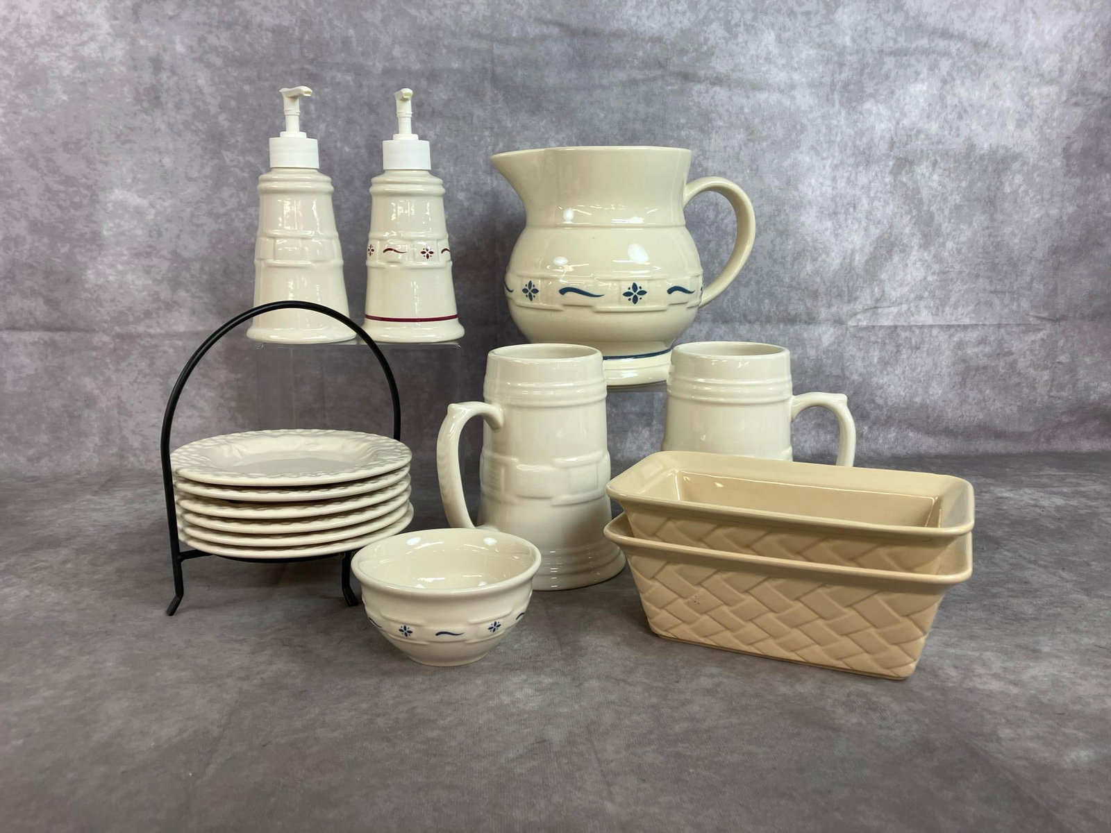 Cream Colored Pottery Collection: Fourteen pieces of late 1900's pottery. Longaberger pieces include pitcher, pump dispensers, two mugs, and small bowl. Caddy with 6 small plates by Signature Housewares and small baking dishes by