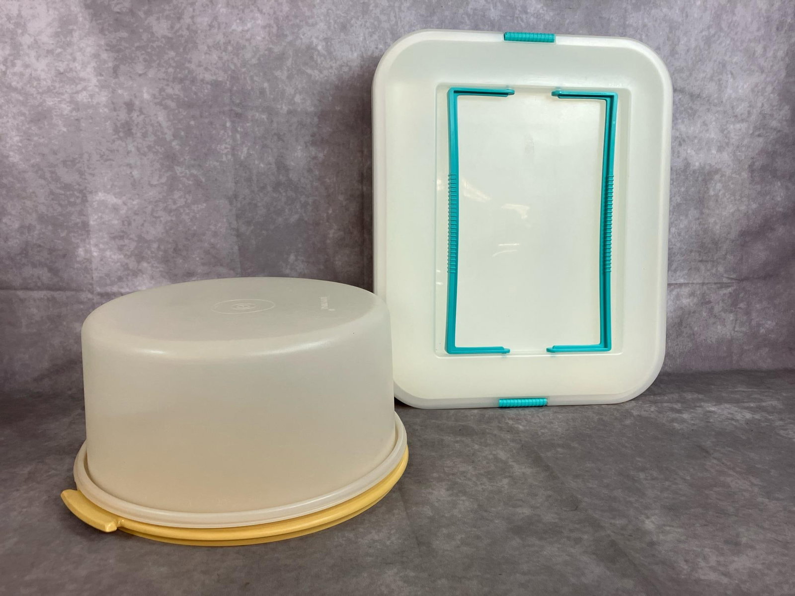 Cake Takers: Two large cake carriers. Tupperware large round cake taker and large plastic rectangular cake carrier with aqua handles. Both in good condition. Rectangular box measures 16 inches wide x 19 x 3.25