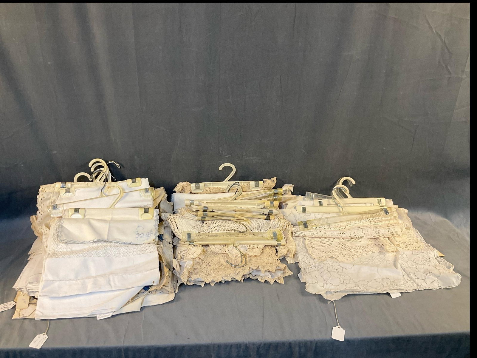 Assorted Textiles: Lot of approximately twenty assorted textiles including; Quilt pieces, linens, napkins, doilies, and a Battenburg Shay. Good condition on hangers. Most measure approximately 14 inches wide x 14 inches