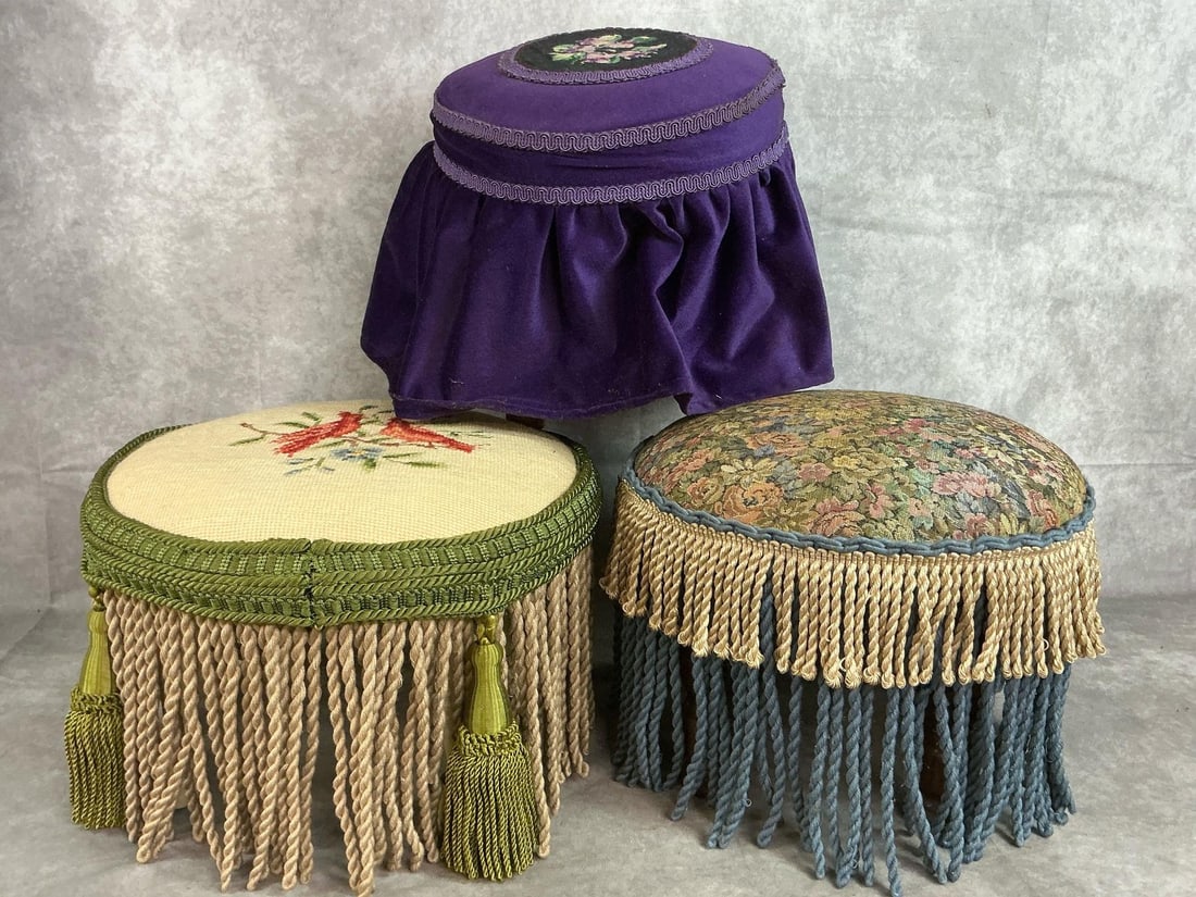 Victorian Style Footstools: Three vintage footstools or ottomans. Two have needlepoint art, the other is fabric cushioned. Wooden legs and fringe. Slight wear, otherwise in good condition. Green and brown stool measures 14