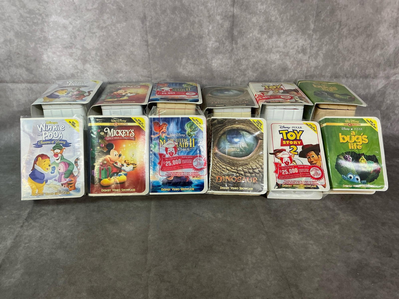 McDonald's Disney Figures: Twenty-four 2000 year "book style" Happy Meal toys. Disney Showcase includes A Bug's Life, Toy Story 2, Dinosaur, Little Mermaid II, Mickey's Christmas, and Winnie the Pooh. In original packs, some
