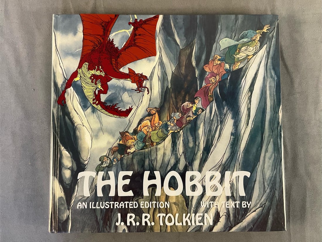 The Hobbit Illustrated/Tolkien: 1977 edition of J.R.R. Tolkien's "The Hobbit” with original mailing cardboard box from Abram's Publishing House. Original plastic dust jacket. Good condition. Measures 11.75 inches wide x 1 x