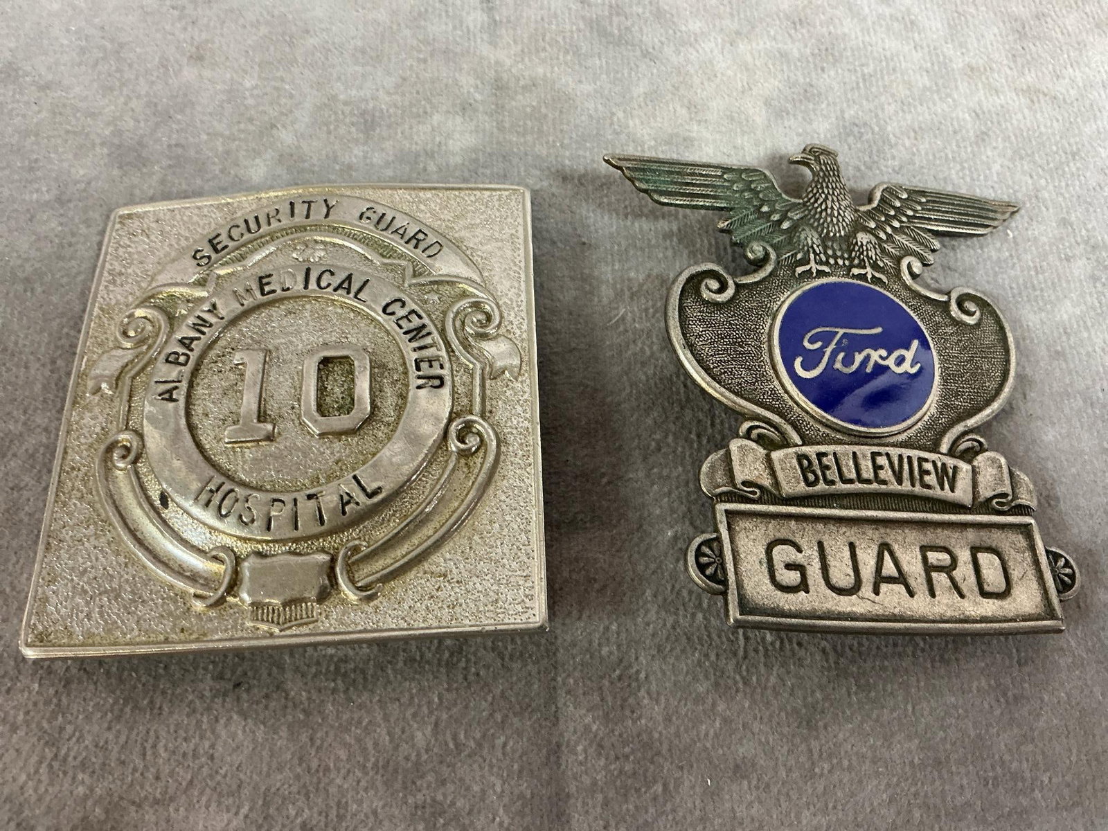Security Badges: Two vintage guard badges. Security Guard for Albany Medical Center #10, and Ford Belleview Guard metal badges. In good condition. Square badge measures 2.5 inches wide x 2.75 inches tall.