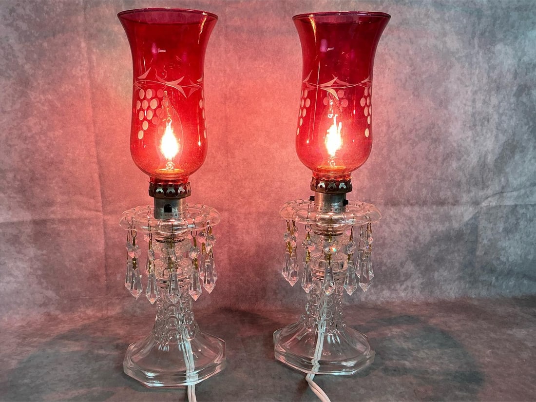 Cranberry Luster Lamps: Pair of vintage glass boudoir lamps. Cranberry shades with grapes etching, glass base with crystal prisms. In good condition. Each measures 5 inches in diameter x 15 inches tall.