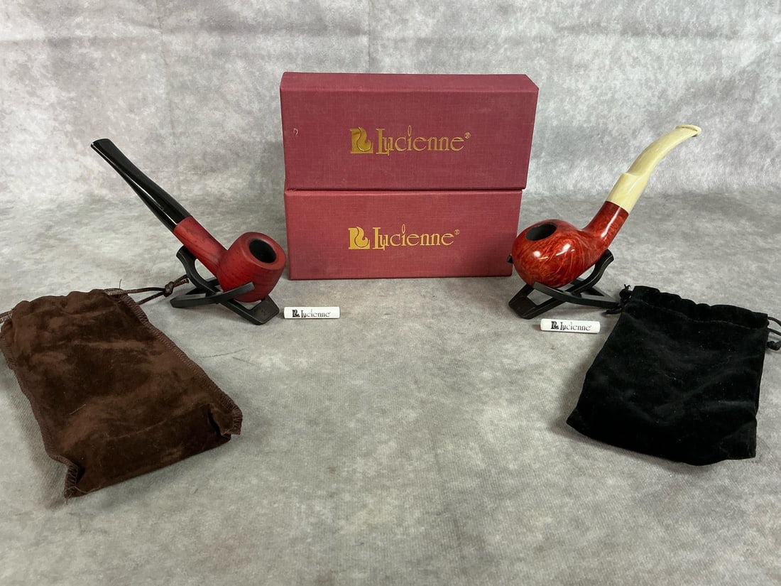 Lucienne Tobacco Pipes: Two new tobacco pipes by Lucienne. Calabash inspired briarwood pipe with cream acrylic stem, and a straight bit and stem dark red briarwood pipe. Both in original box with bag and stand included. Box