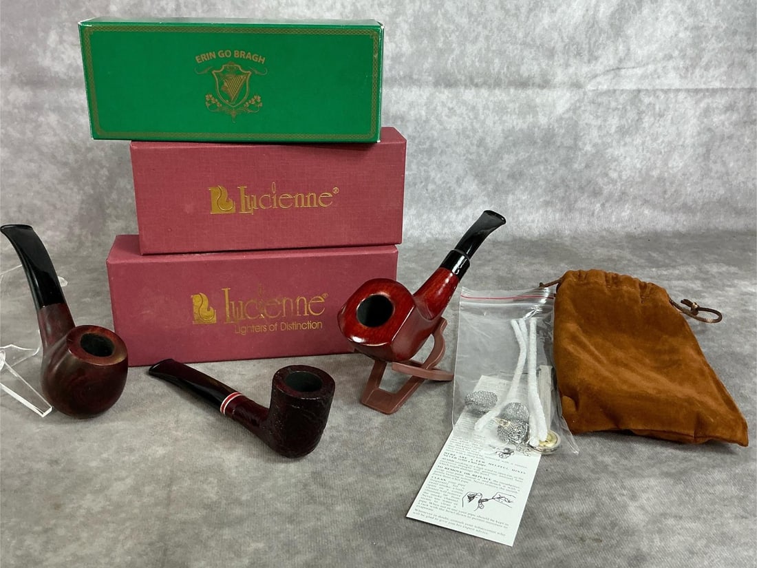 Lucienne & Erin Go Braugh Tobacco Pipes: Three new collectible tobacco pipes. Two Lucienne polished briarwood pipes in original box. Erin Go Bragh rustic look wooden pipe with black stem and red band. All are unsmoked. Box measures 6.5