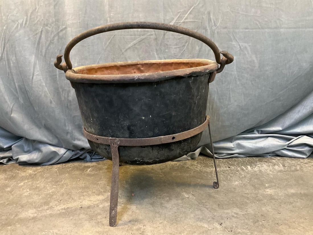 Apple Butter Kettle: 19th century copper and wrought iron dovetailed apple butter kettle on period wrought iron tripod stand. Approximately 20 gallon capacity, not measured. Several old riveted repairs with some dents, no