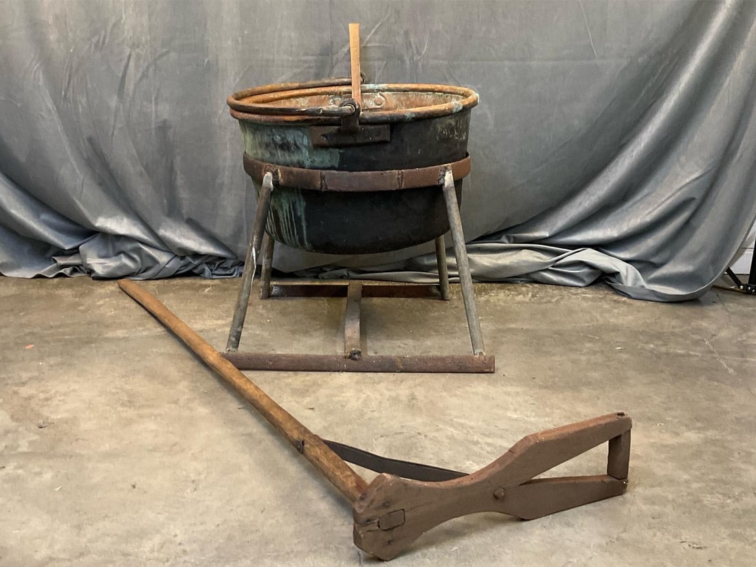 Apple Butter Kettle: 19th century copper and wrought iron dovetailed apple butter kettle on welded iron stand. Includes two apple butter stirrers. Approximately 20 gallon capacity, not measured. Dented, not tested,
