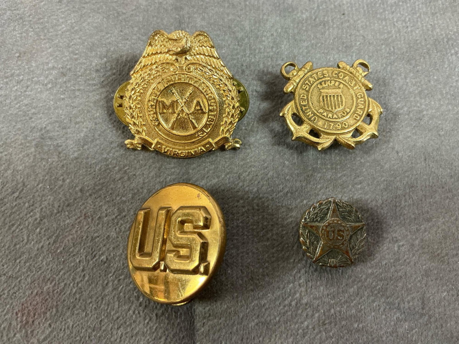 VMI Badge, WWI Pin, and More: Four vintage badges or pins. Virginia Military Academy cap badge, WWI Army Honorable Discharge Lapel pin, Coast Guard badge, and U S Army collar insignia. In good condition. VMI badge measures 1.25