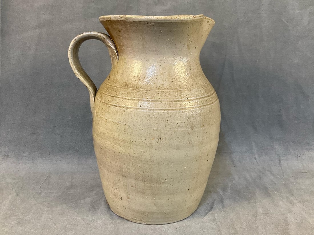 Stoneware - North Carolina Pitcher: Mid-Late 19th century North Carolina Salt Glazed Pitcher with light orange peel effect and strap handle. Possibly Randolph County/J.D. Craven. Good condition. Measures 6.25 inches in diameter x 10.5