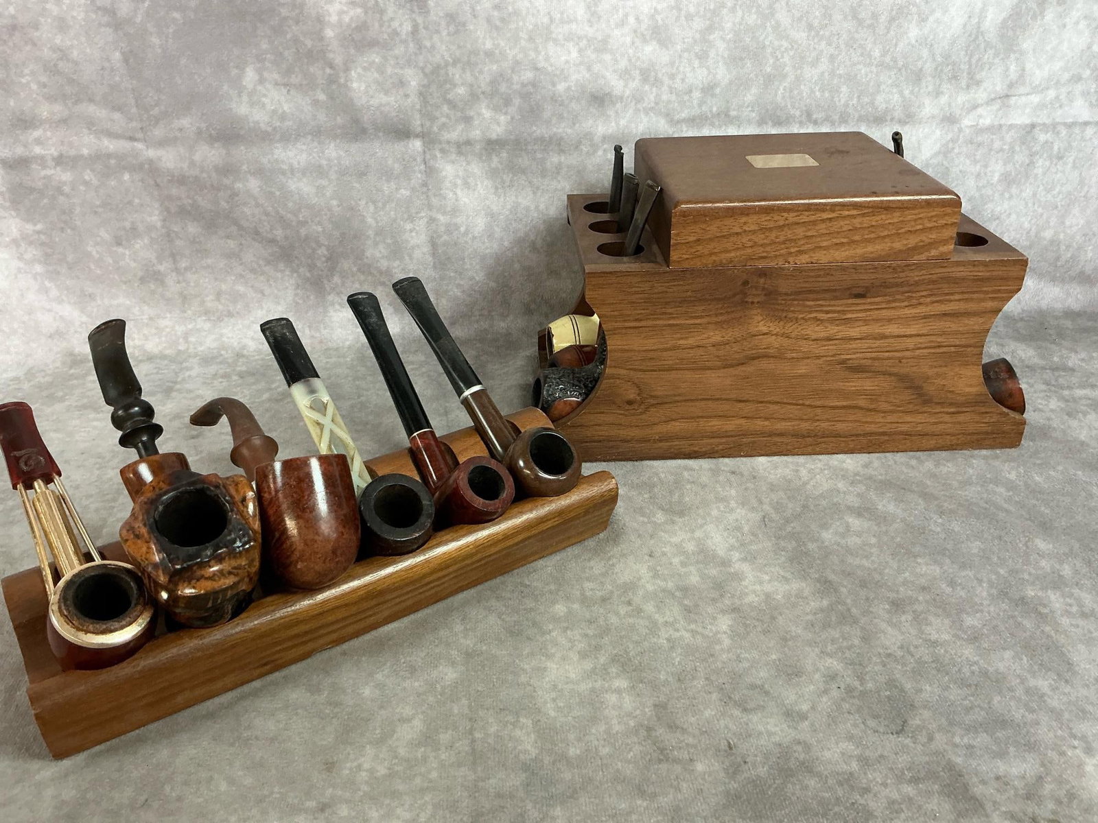Collectible Pipes & Stands: Mid to late 1900's tobacco pipes and stands. Twelve pipes including a Nylon estate pipe, Nording Fantasy briar pipe, Garland pipe, Medico Apollo pipe, and more. Hinged walnut humidor stand and walnut 