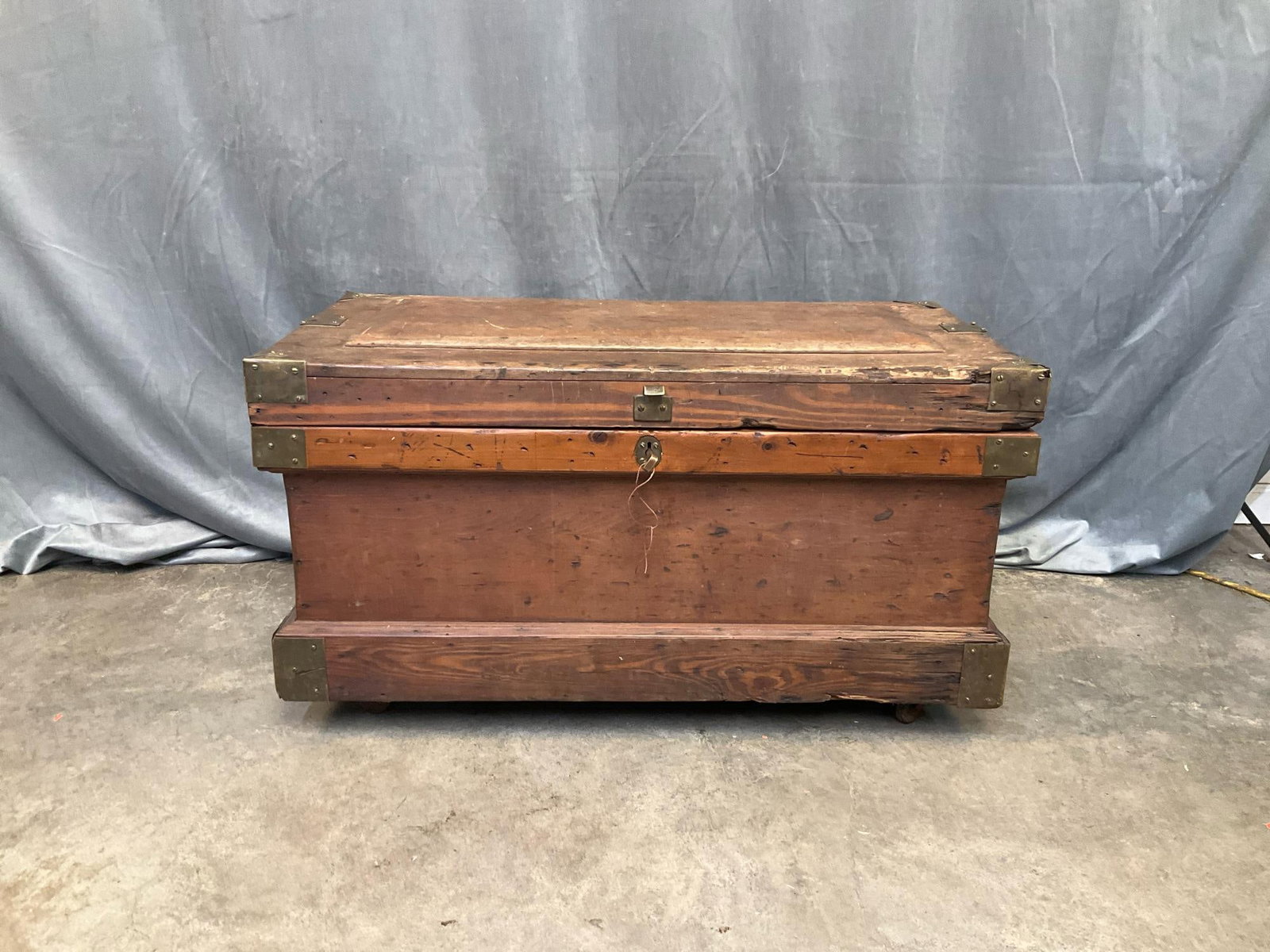 Tool Chest - Victorian Period: Late 19th century pine tool chest with protective brass corners, cast iron decorative carrying handles, and castors. Original lock and key present, not in working order, and several losses to brass