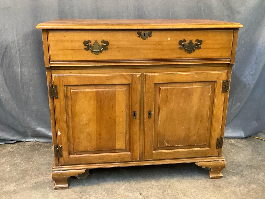 Chest: Mid-20th century chest with lift top storage area and lower cupboard with working key for the three locks. Scratches and wear to finish, missing veneer, hole in backboard,and missing castor. Measures
